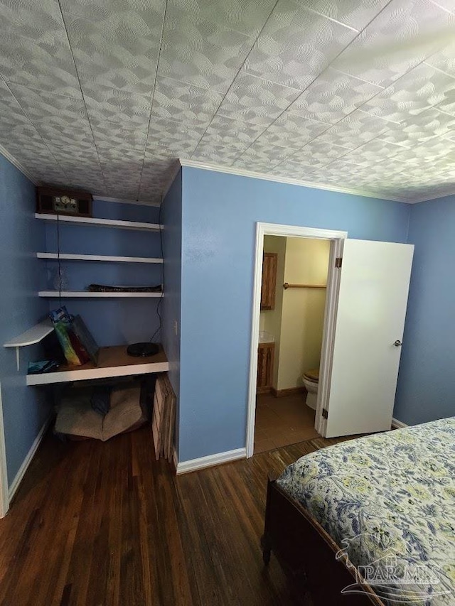 bedroom featuring ensuite bath and dark hardwood / wood-style floors