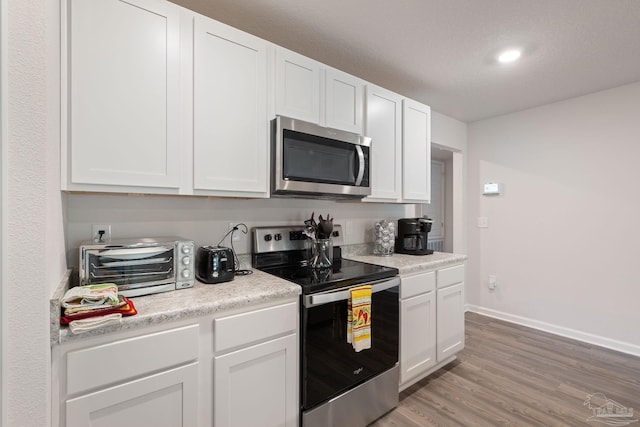 kitchen featuring light wood-type flooring, white cabinetry, and stainless steel appliances