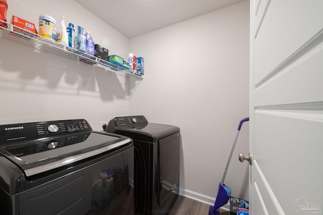 clothes washing area featuring washing machine and clothes dryer and dark wood-type flooring