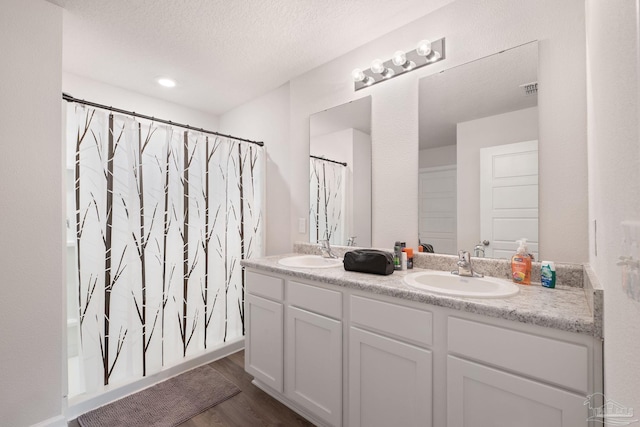 bathroom featuring hardwood / wood-style floors, vanity, and a textured ceiling