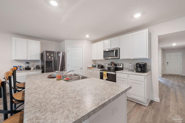 kitchen featuring white cabinets, a center island with sink, sink, and appliances with stainless steel finishes