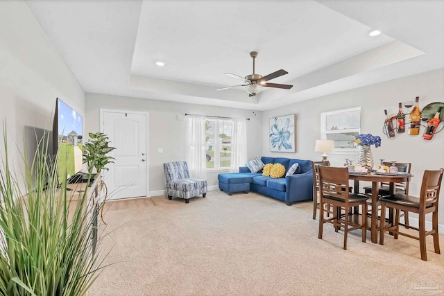 carpeted living room with a raised ceiling, a ceiling fan, baseboards, and recessed lighting