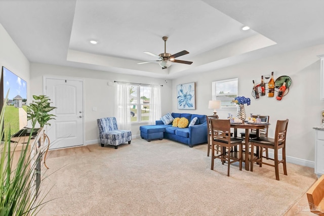 living room with a tray ceiling, a ceiling fan, light colored carpet, baseboards, and recessed lighting