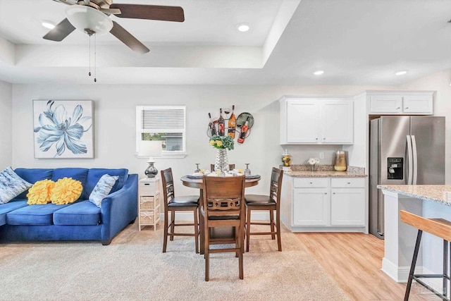 dining room featuring light wood finished floors, ceiling fan, recessed lighting, and a raised ceiling