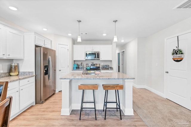kitchen with appliances with stainless steel finishes, white cabinetry, a kitchen island with sink, and recessed lighting