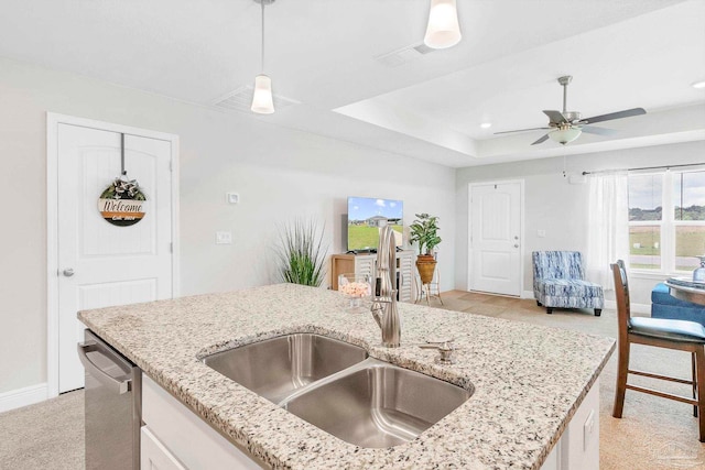 kitchen featuring a sink, baseboards, a tray ceiling, light stone counters, and pendant lighting