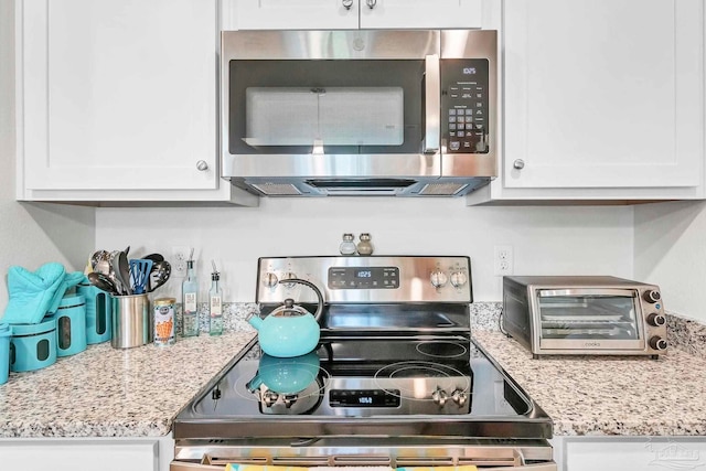 kitchen with appliances with stainless steel finishes, white cabinets, and light stone countertops
