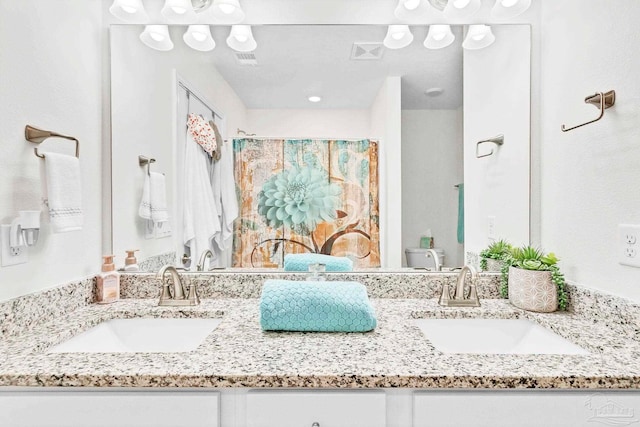 full bathroom with toilet and double vanity