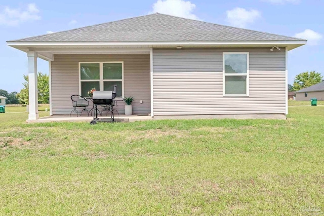 rear view of property featuring a shingled roof and a yard