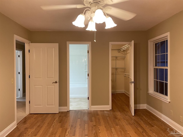 3036 Laurel Dr, Gulf Breeze, FL 32563 - unfurnished bedroom featuring a spacious closet, a closet, wood finished floors, baseboards, and ceiling fan