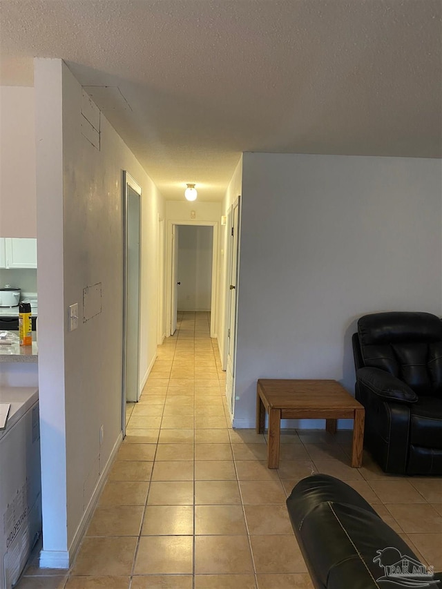 hall with light tile patterned floors and a textured ceiling