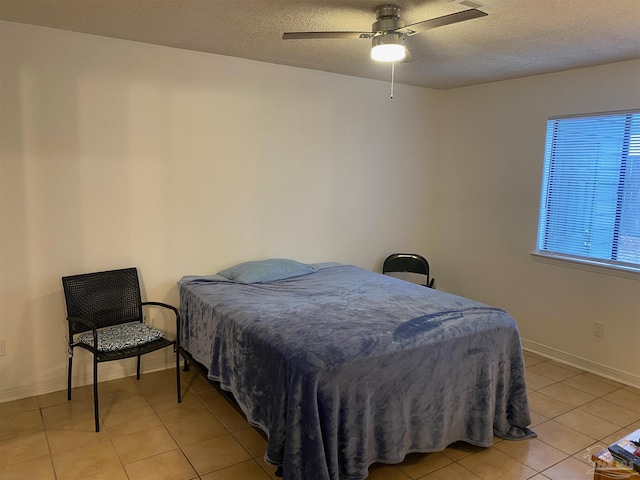 bedroom featuring a textured ceiling, ceiling fan, and light tile patterned floors