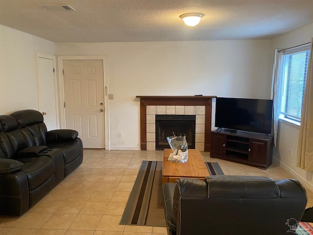 tiled living room with a tile fireplace and a textured ceiling