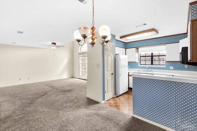 kitchen featuring pendant lighting, white refrigerator, light colored carpet, and white cabinetry