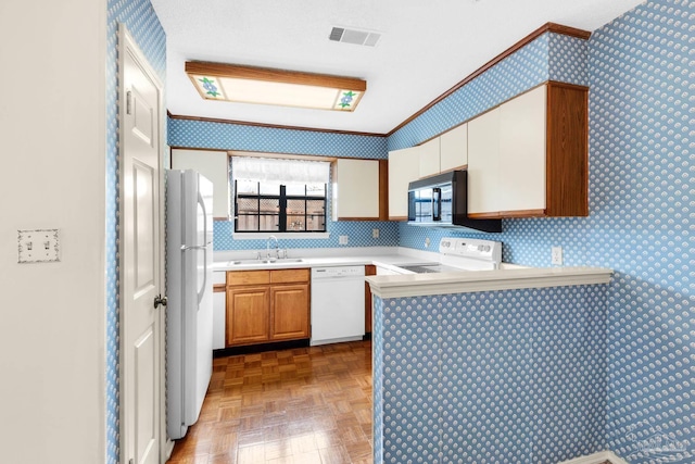 kitchen featuring parquet flooring, white appliances, kitchen peninsula, and sink