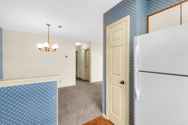 kitchen featuring decorative light fixtures, white refrigerator, light colored carpet, and a chandelier