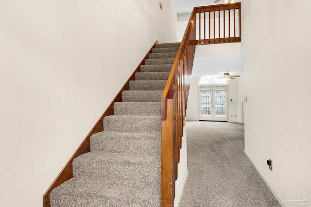 stairs with ceiling fan, carpet floors, a high ceiling, and french doors