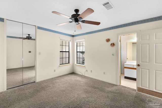 unfurnished bedroom with ensuite bath, ceiling fan, a closet, and light colored carpet