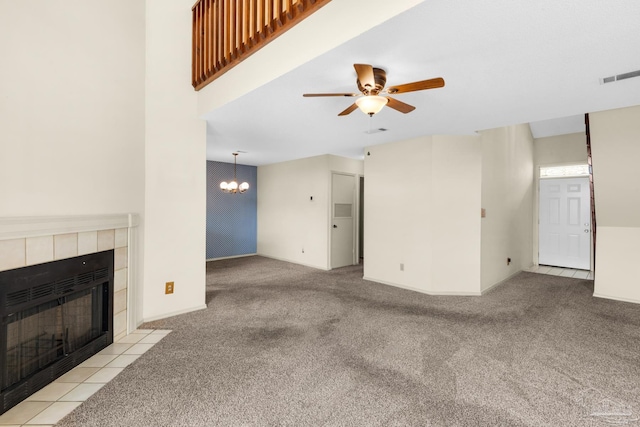 unfurnished living room featuring a fireplace, light carpet, and ceiling fan with notable chandelier