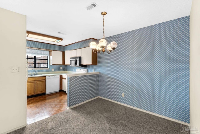 kitchen featuring dishwasher, stove, parquet floors, sink, and decorative light fixtures