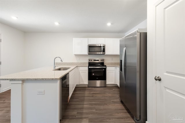 kitchen featuring stainless steel appliances, a sink, a peninsula, dark wood-style flooring, and recessed lighting