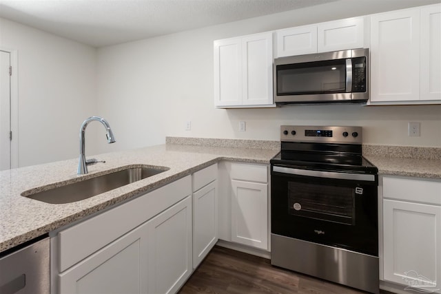 kitchen featuring appliances with stainless steel finishes, a sink, white cabinetry, and dark wood-type flooring
