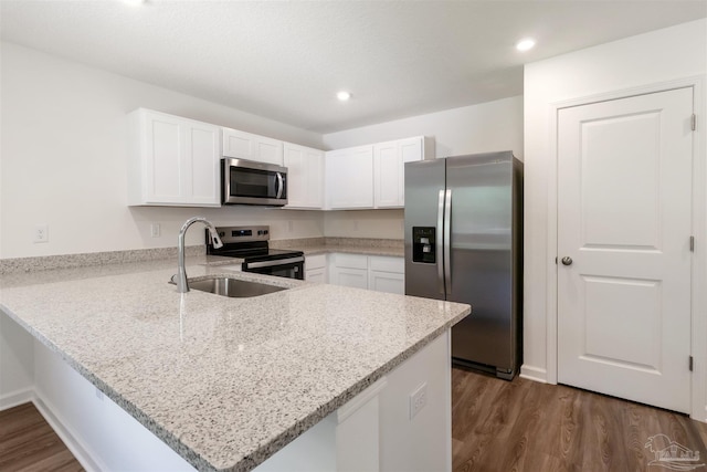kitchen featuring appliances with stainless steel finishes, a peninsula, dark wood-type flooring, white cabinets, and recessed lighting
