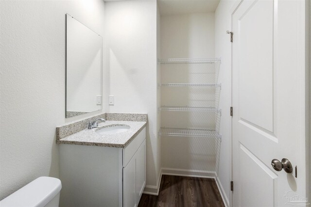 bathroom featuring vanity, wood finished floors, toilet, and baseboards