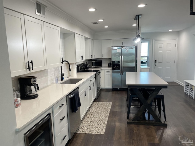 kitchen with beverage cooler, a sink, tasteful backsplash, dark wood finished floors, and stainless steel appliances