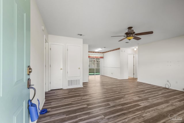 empty room with visible vents, dark wood finished floors, and ceiling fan