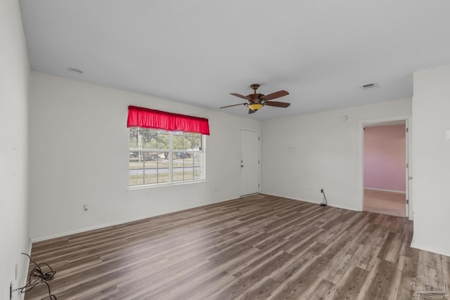 unfurnished room with ceiling fan, visible vents, and wood finished floors