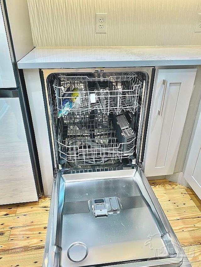 interior details featuring stainless steel refrigerator, dishwasher, and hardwood / wood-style flooring