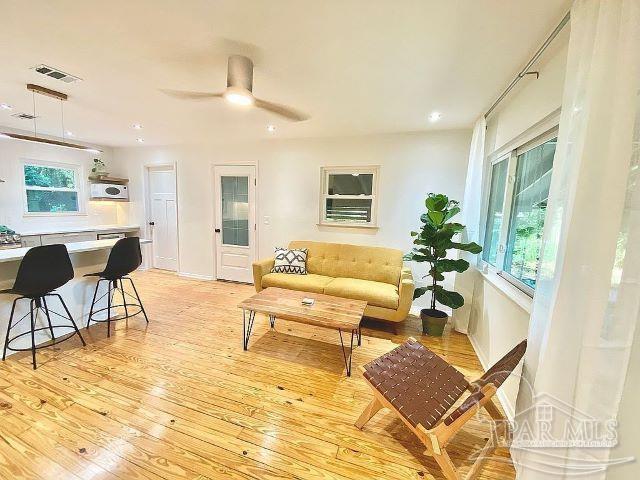 living room with a wealth of natural light, light hardwood / wood-style floors, and ceiling fan