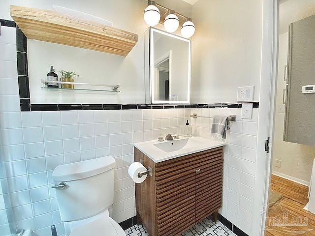 bathroom with tile walls, wood-type flooring, vanity, and toilet