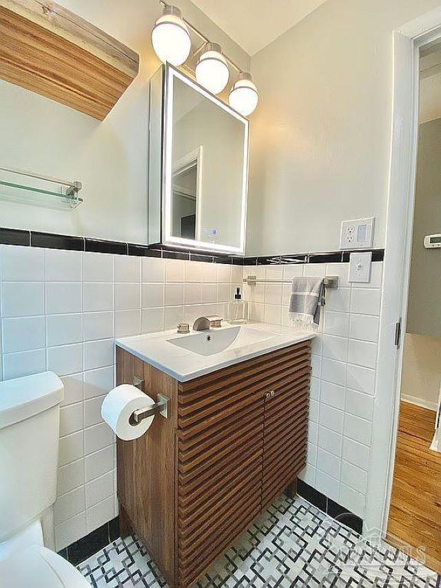 bathroom featuring tile walls, vanity, toilet, and wood-type flooring