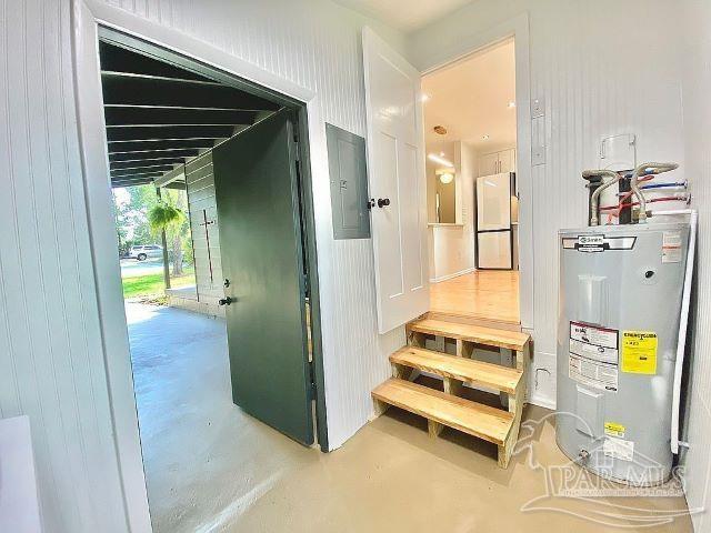 staircase with electric panel, concrete floors, and electric water heater