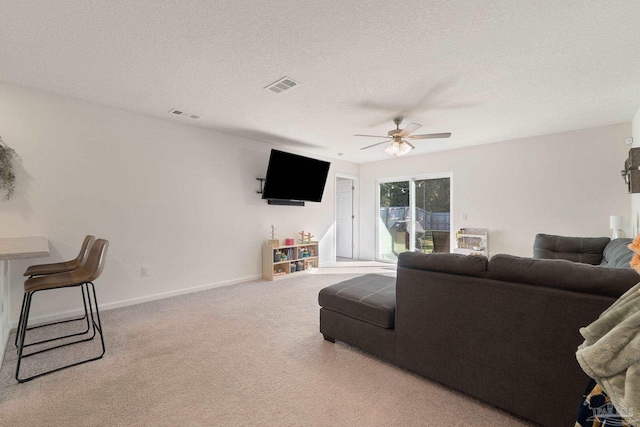 living area with baseboards, visible vents, a ceiling fan, a textured ceiling, and carpet flooring