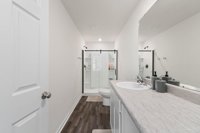 bathroom featuring baseboards, toilet, wood finished floors, vanity, and a shower stall