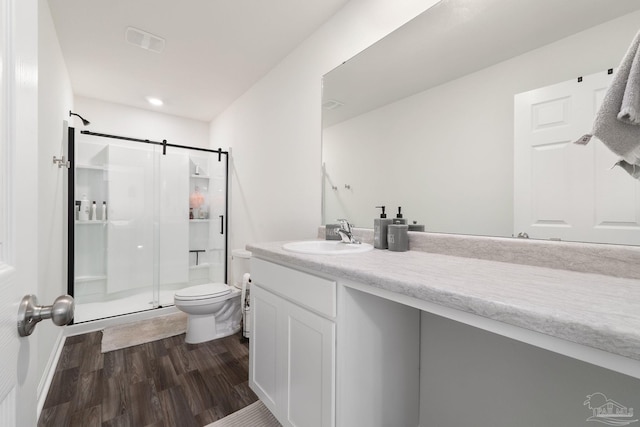 full bathroom with a stall shower, visible vents, toilet, wood finished floors, and vanity