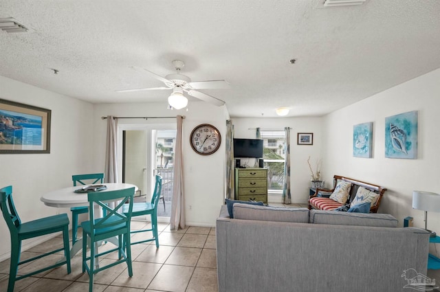 living room featuring ceiling fan, light tile patterned floors, and a textured ceiling