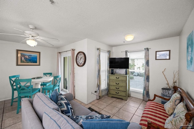 living room with ceiling fan, light tile patterned floors, and a textured ceiling