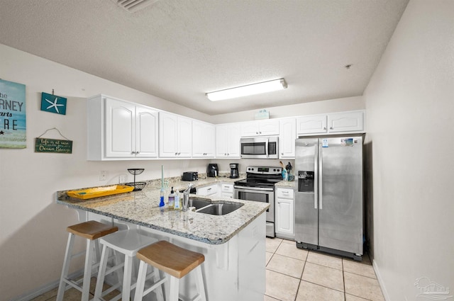 kitchen featuring sink, a textured ceiling, white cabinetry, kitchen peninsula, and stainless steel appliances