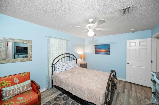 bedroom featuring hardwood / wood-style floors, ceiling fan, and a textured ceiling