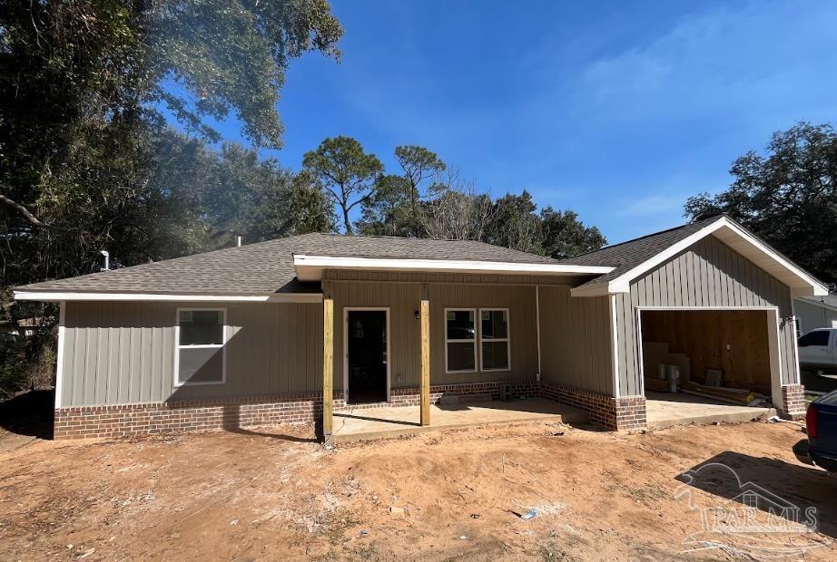 ranch-style house with a garage, a shingled roof, and a patio