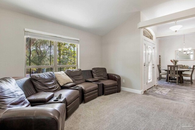 living area with baseboards, vaulted ceiling, a notable chandelier, and light colored carpet