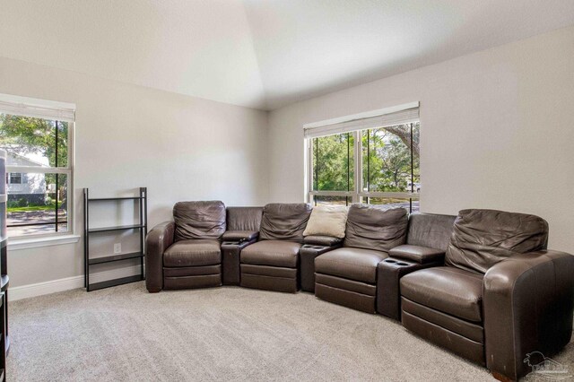 home theater with light colored carpet, vaulted ceiling, and baseboards