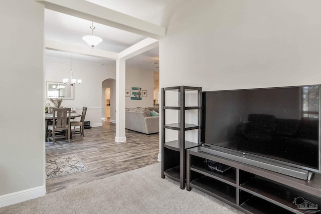 interior space featuring arched walkways, a notable chandelier, wood finished floors, and baseboards