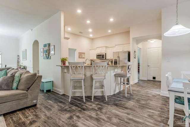 kitchen featuring kitchen peninsula, dark hardwood / wood-style flooring, ornamental molding, a breakfast bar, and stainless steel appliances