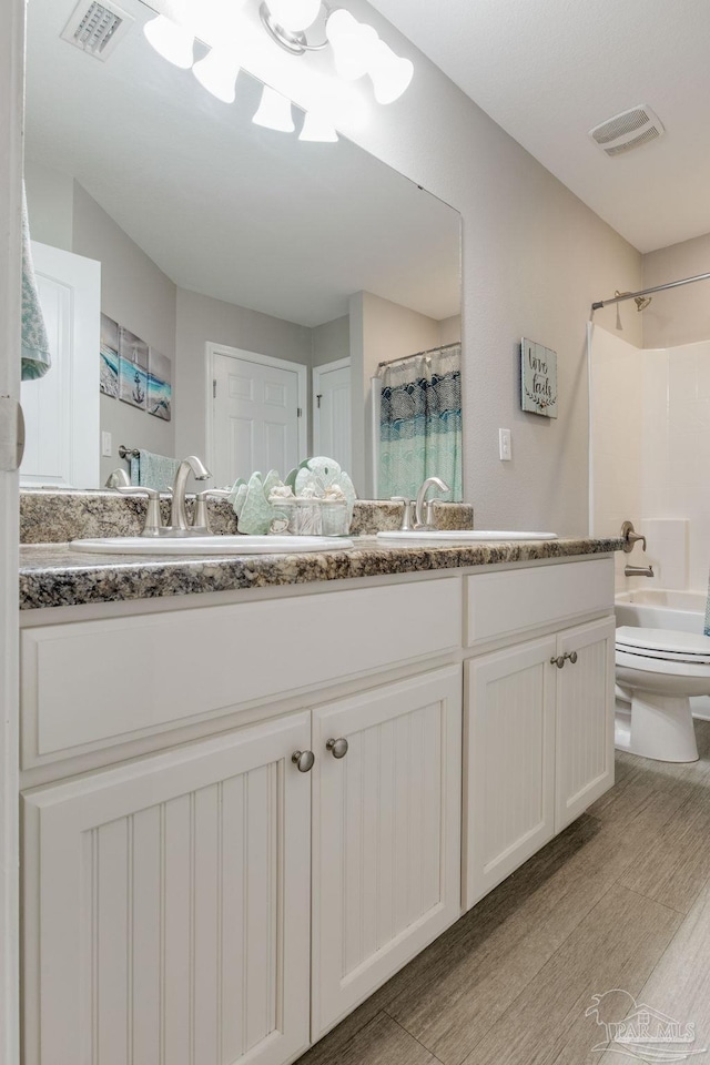 full bathroom with shower / bath combination with curtain, vanity, hardwood / wood-style flooring, and toilet