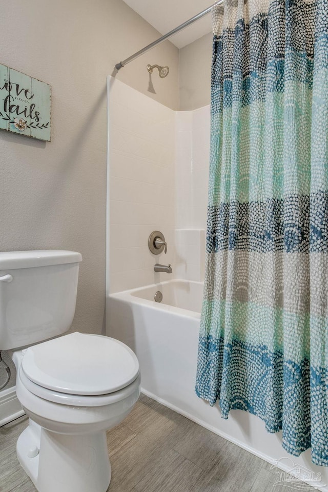 bathroom with hardwood / wood-style flooring, shower / bathtub combination with curtain, and toilet